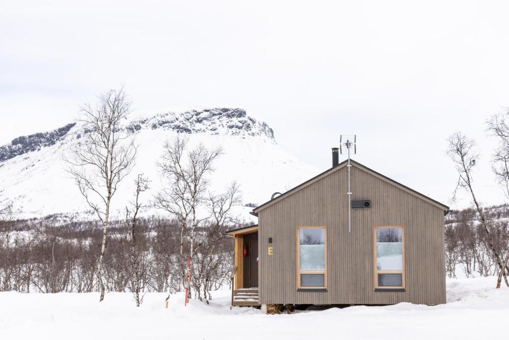 una cabina nella neve con una montagna sullo sfondo di Villa Naali E a Kilpisjärvi