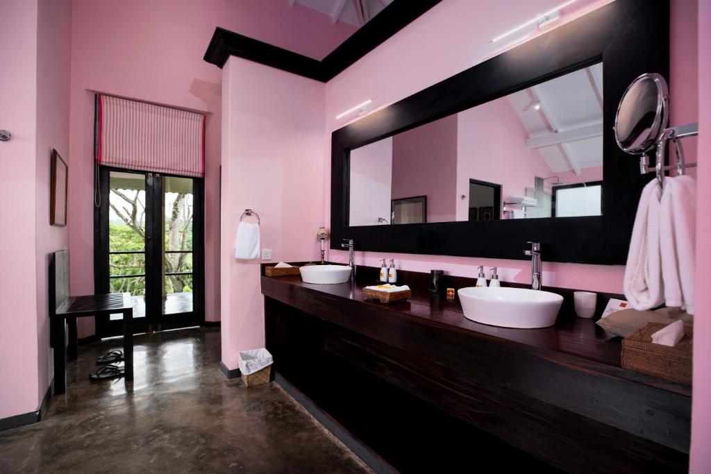 a bathroom with three sinks and a large mirror at Kahanda Kanda in Koggala