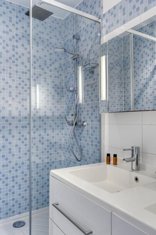 W łazience znajduje się umywalka i prysznic z niebieskimi kafelkami. w obiekcie 3 Rooms with Sea View Terraces in Peace w Saint-Tropez