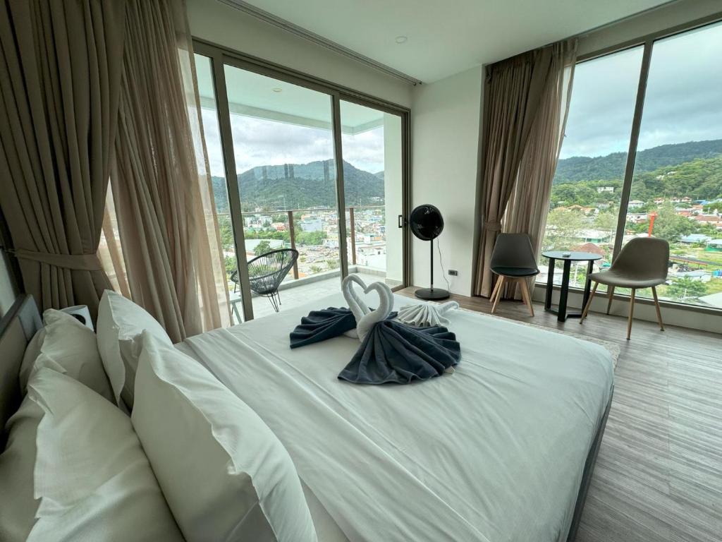 Un dormitorio con una cama blanca con una ventana grande. en Apartment with panoramic views at Oceana by Lofty, en Kamala Beach