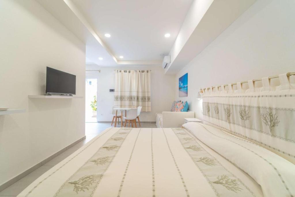 Una habitación blanca con una cama y un televisor. en La Stampa Room, en Olbia