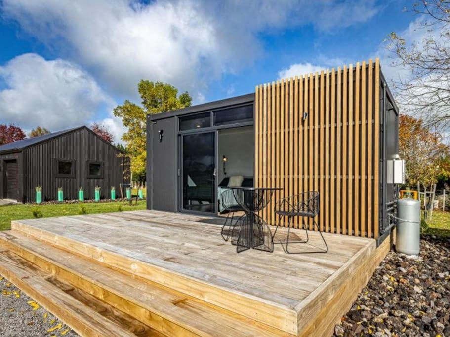 a house with a wooden deck with a table on it at Rural retreat - Tahi cabin in Ohakune