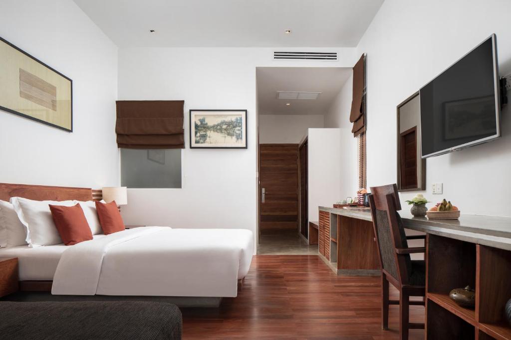 a bedroom with a bed and a desk and a television at Lynnaya Urban River Resort in Siem Reap