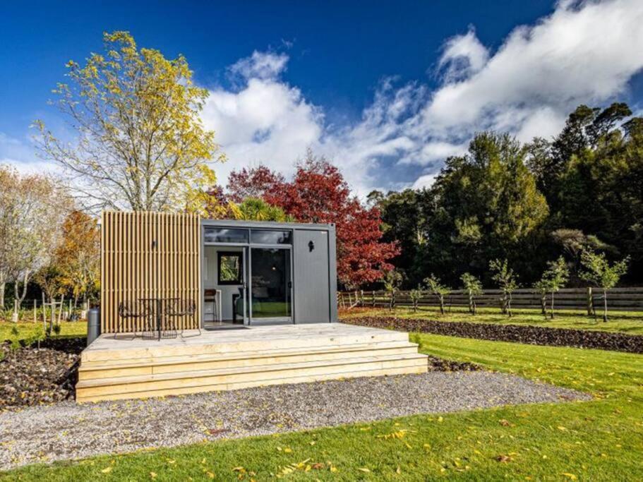 a small cabin in a field with trees in the background at Rural retreat - Rua cabin in Ohakune