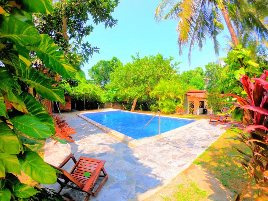 a swimming pool with two chairs and a table at Dambullawatha Bungalow Garden Villa in Hikkaduwa