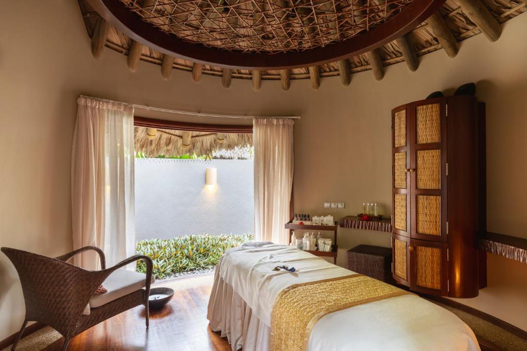 a bedroom with a bed and a large window at Constance Ephelia in Port Glaud