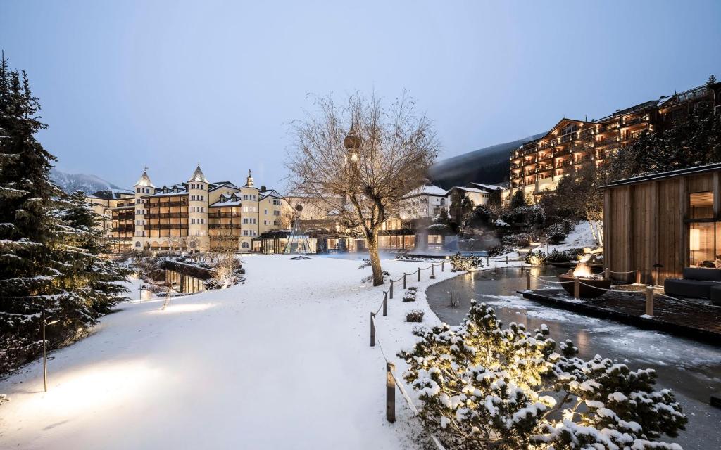 a park covered in snow with buildings in the background at Adler Spa Resort Dolomiti in Ortisei