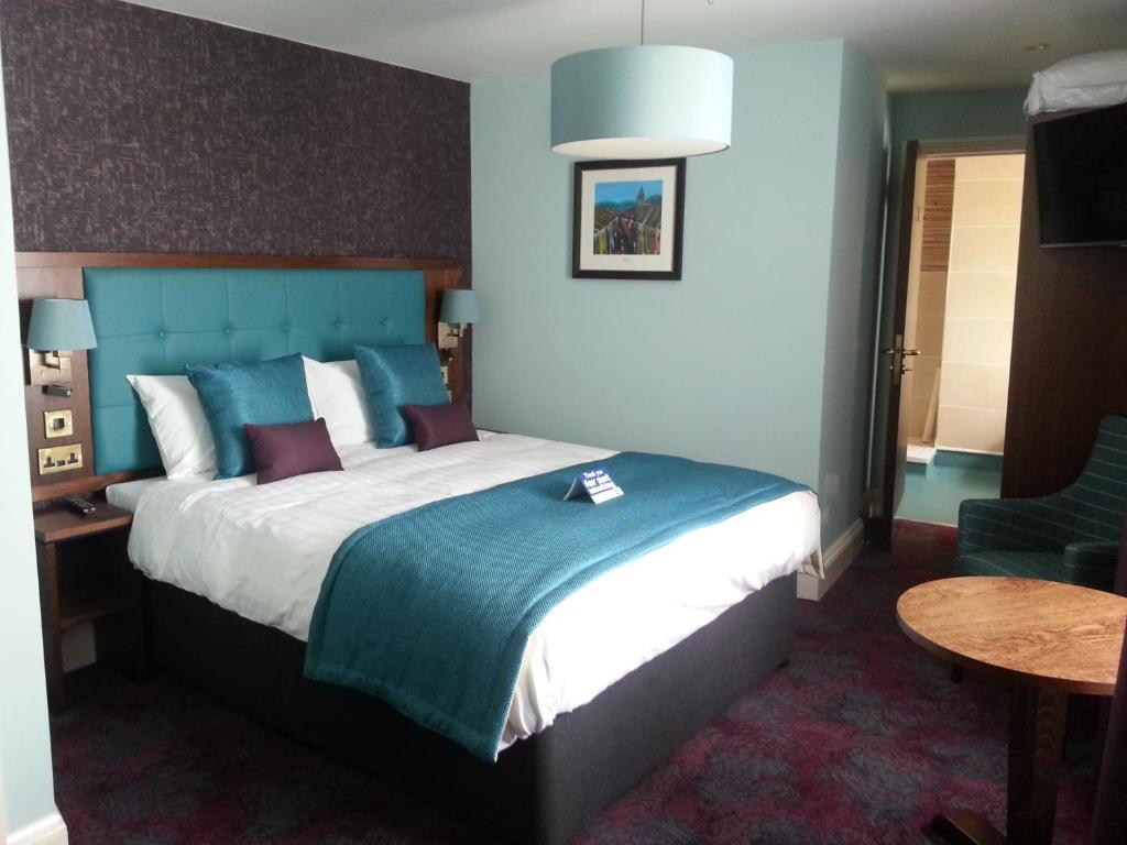 um quarto com uma cama grande e uma cabeceira azul em The Queen's Head Wetherspoon em Tavistock