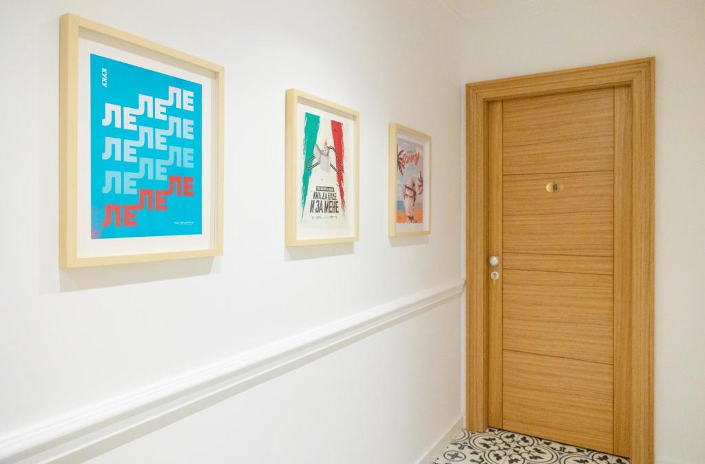 a hallway with a wooden door and pictures on the wall at Lovcevic Apartmani & Sobe in Šabac
