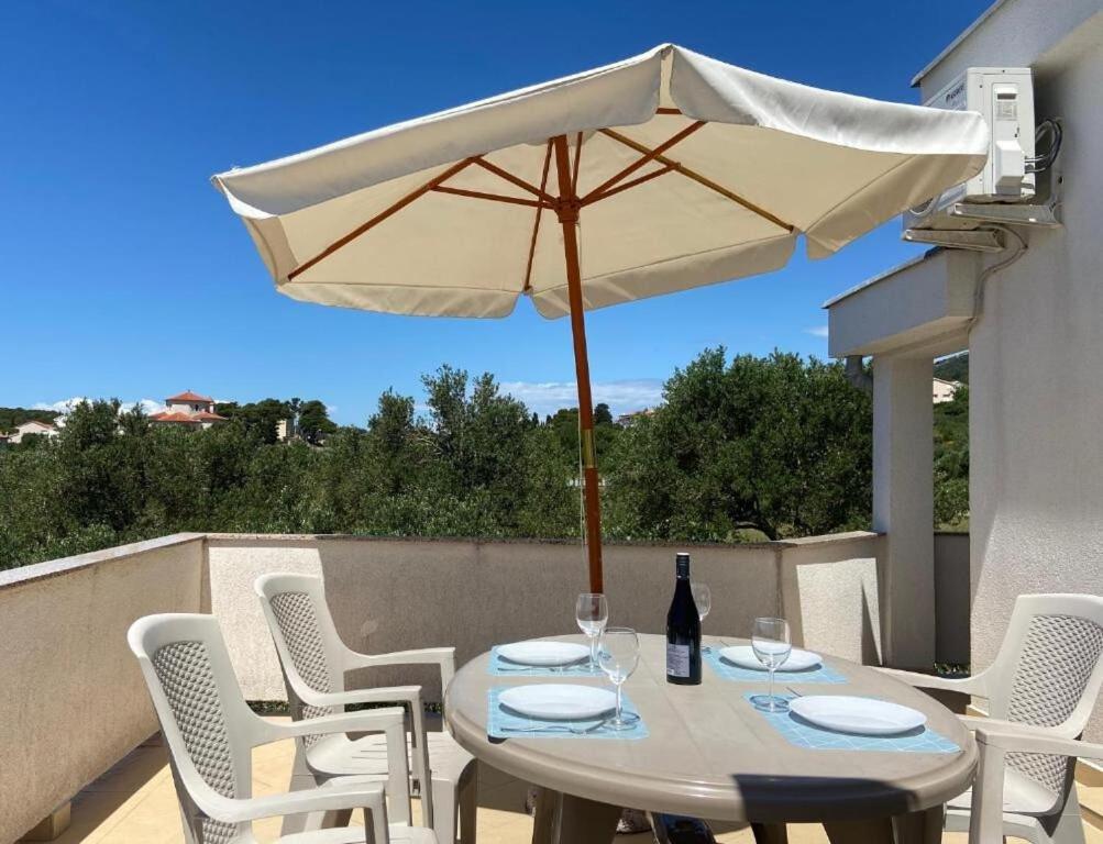 una mesa con sombrilla blanca y sillas blancas en Apartment Zare, en Banjol