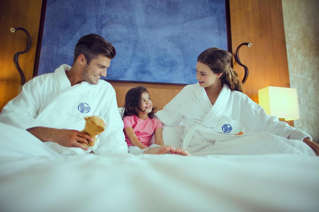 a family sitting in bed with a little girl at Yas Island Rotana Abu Dhabi in Abu Dhabi
