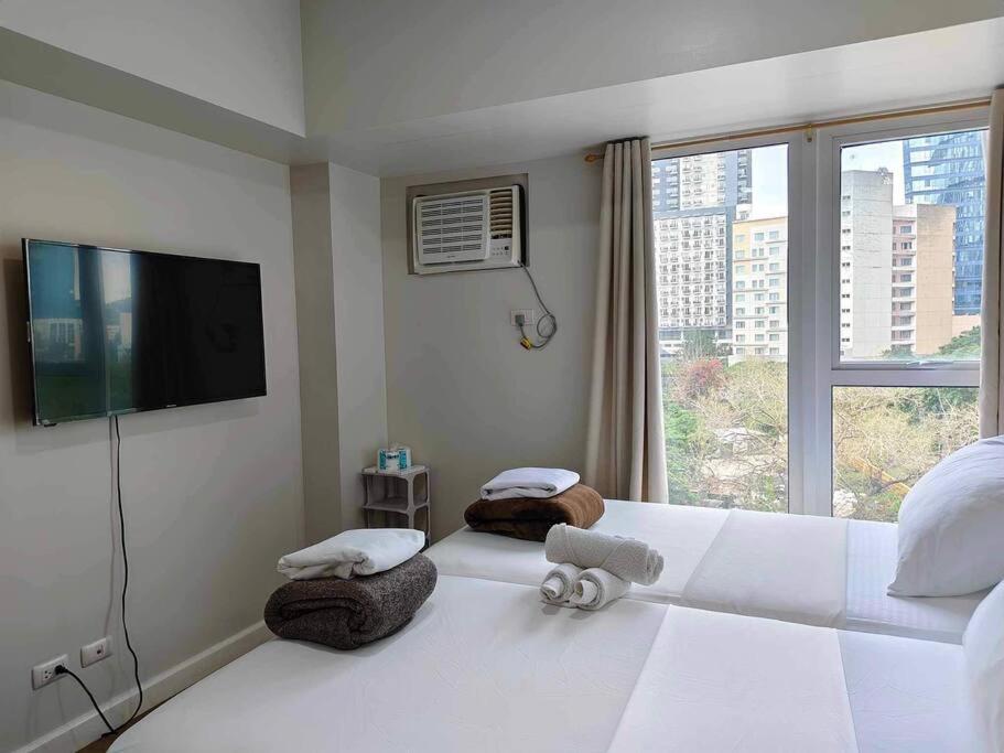 a bedroom with a large white bed with a large window at Solinea T3 805-A Elegant studio in Cebu City