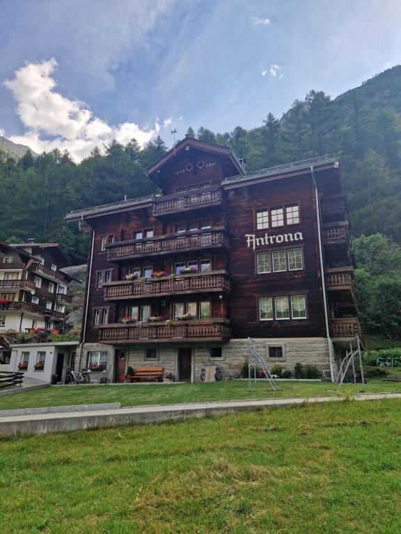 a large wooden building in the middle of a field at Saastal Apartments Haus Antrona in Saas-Almagell