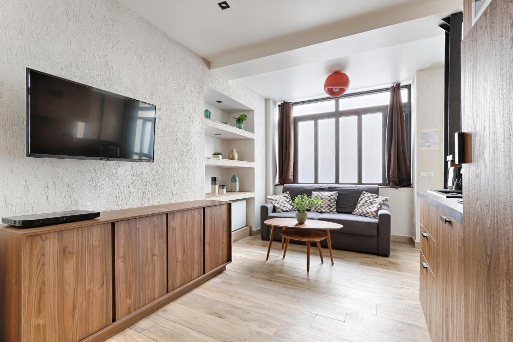 un salon avec un canapé et une télévision sur un mur dans l'établissement Appartement de Charme 2BR Canal Saint Martin, à Paris