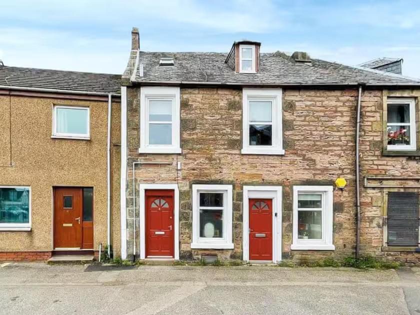 a brick house with red doors on a street at 4 Lower Kessock Street in Inverness