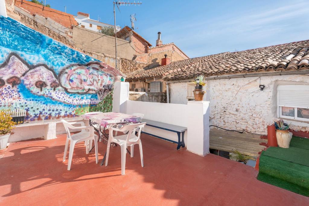 a patio with a table and chairs and a wall with graffiti at Casa Ratón Pérez in Navarrés