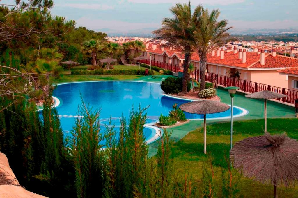 une piscine avec parasols dans un complexe hôtelier dans l'établissement Preciosa casa con terraza y piscina R106 by Novadesta, à Puerto Marino