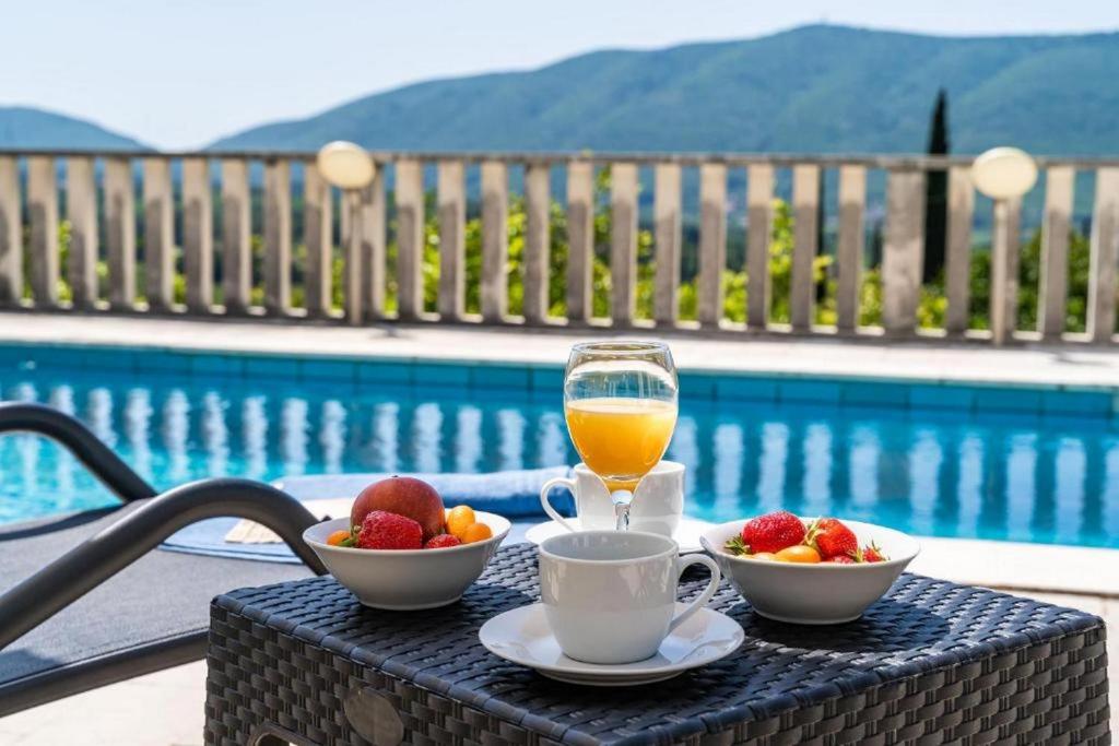 una mesa con un vaso de zumo de naranja y tazones de fruta en Three Bedroom Villa surrounded by Nature with Pool, en Gruda