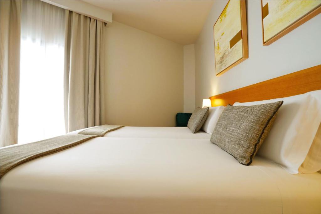 a bedroom with a large white bed with a window at Arc La Rambla in Barcelona