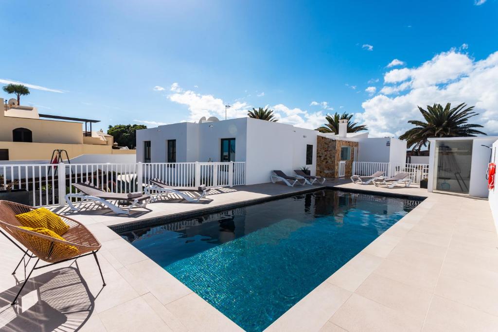 a swimming pool with chairs and a villa at Casa Marina in Costa Teguise