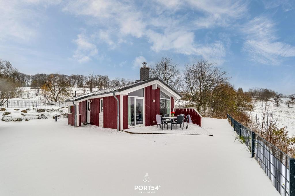 a red house in the snow with tables and chairs at Ferienhaus Bergkristall - Sankt Andreasberg im Harz in Sankt Andreasberg