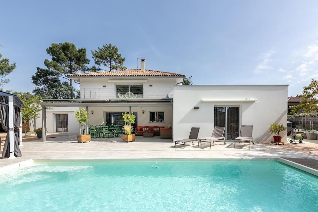 une maison avec une piscine devant une maison dans l'établissement Location Villa Mimizan 10 pers, à Mimizan-Plage