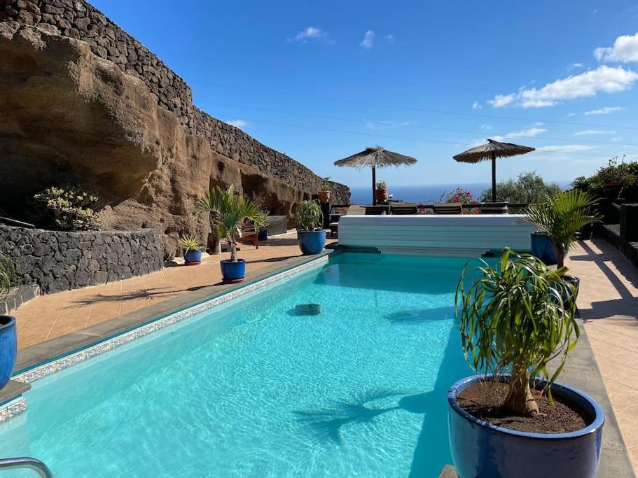 Una piscina con agua azul frente a un muro. en Castillo Lanzarote Villa Antonia, en Tías