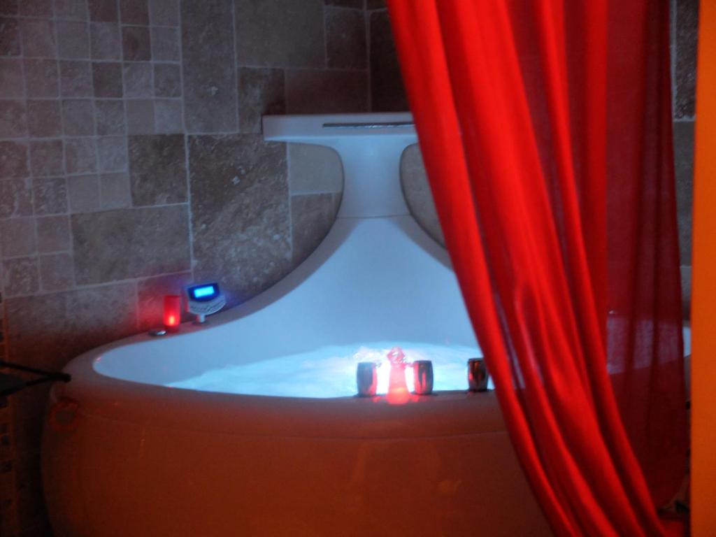 a bathroom with a tub with a red curtain at Une Parenthese pour Deux in Plan-dʼOrgon