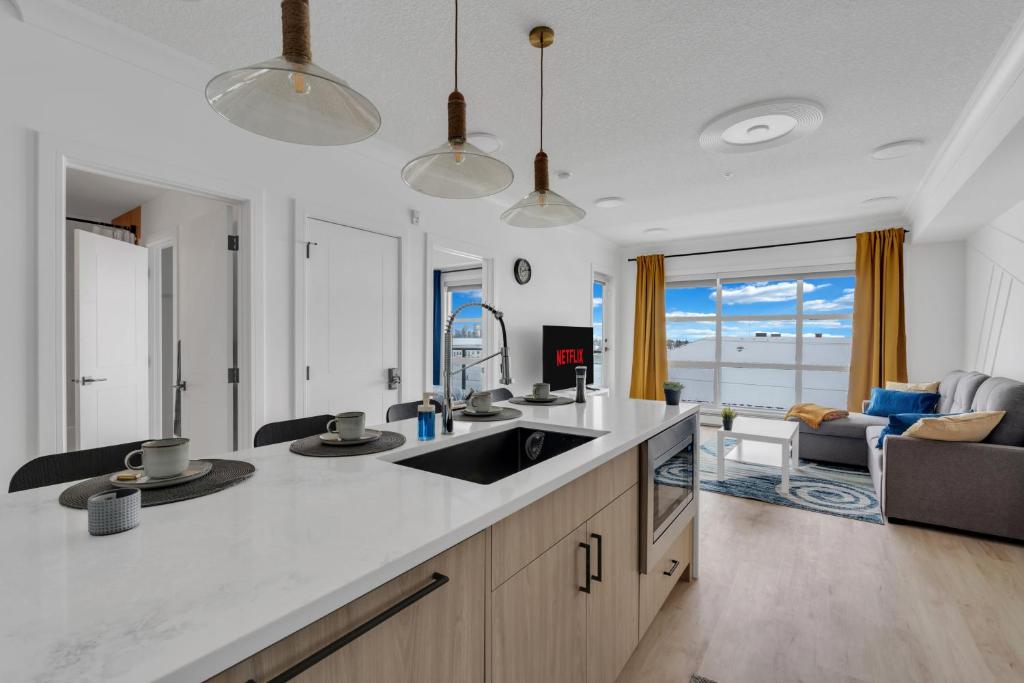 a kitchen with a sink and a living room at Bright Condo with Balcony & Free Parking in Calgary