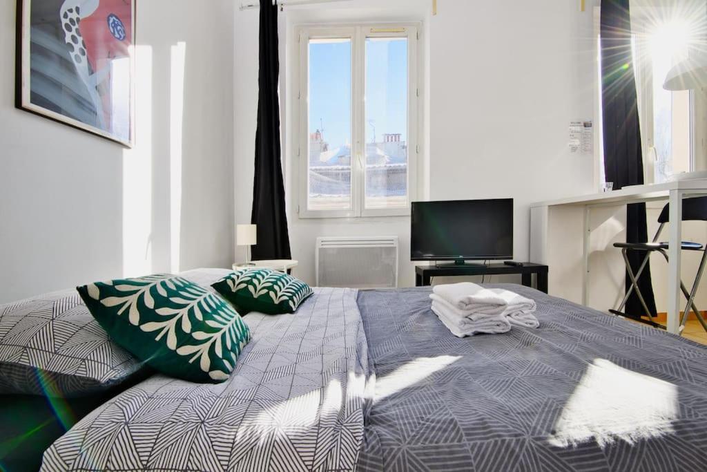 - une chambre avec un lit doté d'oreillers et une télévision dans l'établissement Pied-à-terre idéal au Vieux-Port, à Marseille