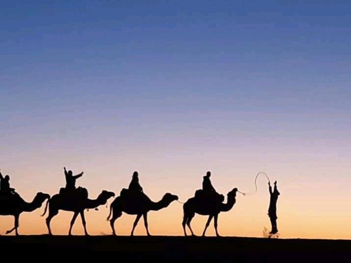 a group of people riding on camels in the desert at Brilliant luxury camp in Merzouga
