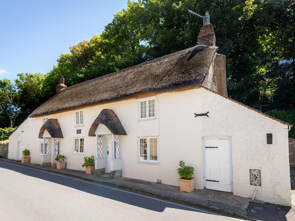 a white cottage with a thatched roof on a street at Amy Cottage in Wareham