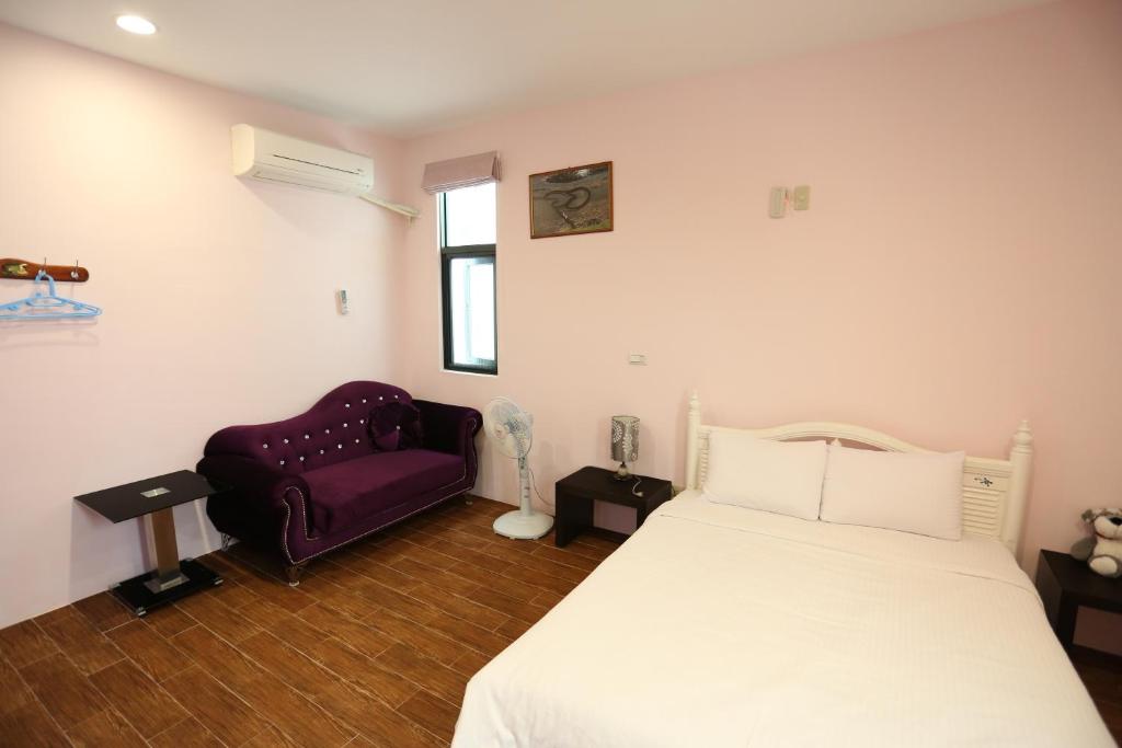 a bedroom with a bed and a purple chair at See Your Dreams B&amp;B in Magong