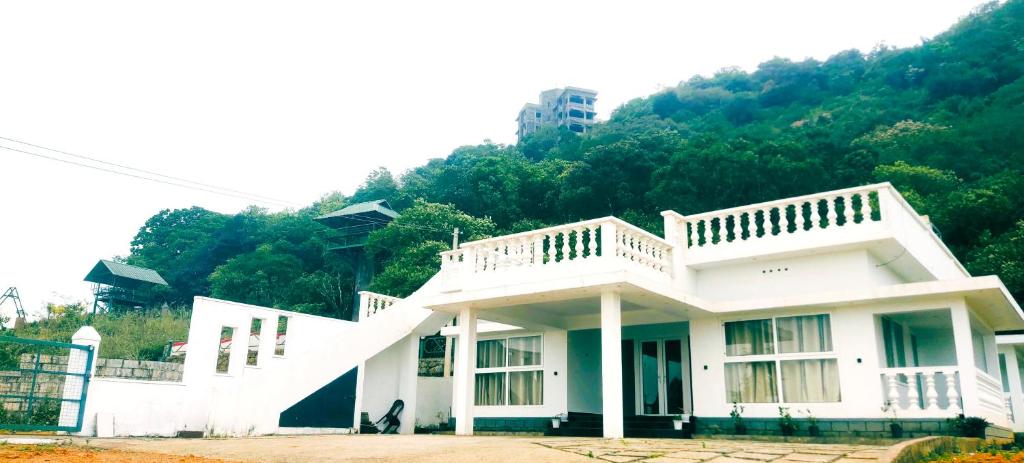 una casa bianca con una collina sullo sfondo di Adithya resort vagamon a Vagamon