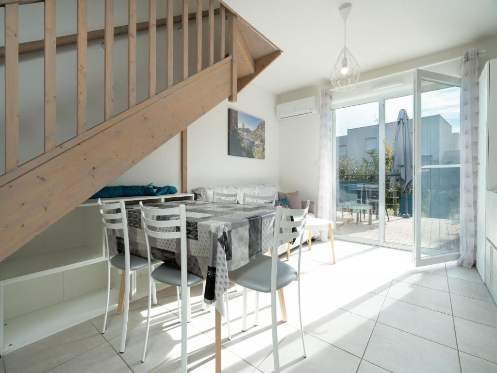 une salle à manger avec une table et des chaises et un escalier dans l'établissement La Dune 48 - Villa 3P6, à Valras-Plage