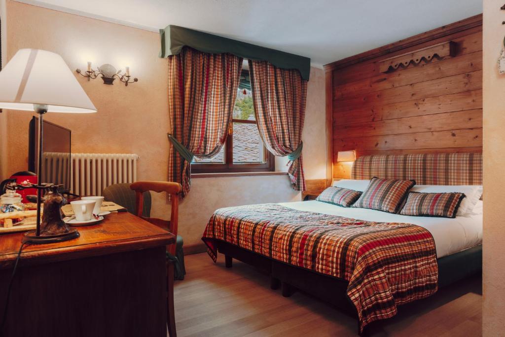a hotel room with a bed and a desk with a lamp at Villa Novecento Romantic Hotel - Estella Hotel Collection & Experience in Courmayeur