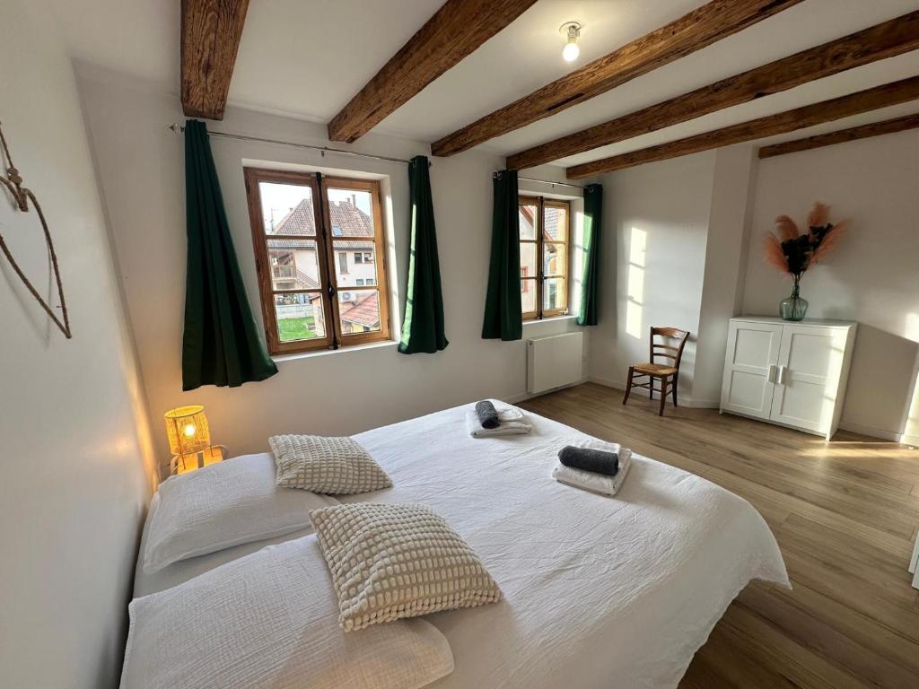a bedroom with a large white bed with two pillows at Les 7 Prunes - Demeure Alsacienne d'Exception in Zellwiller