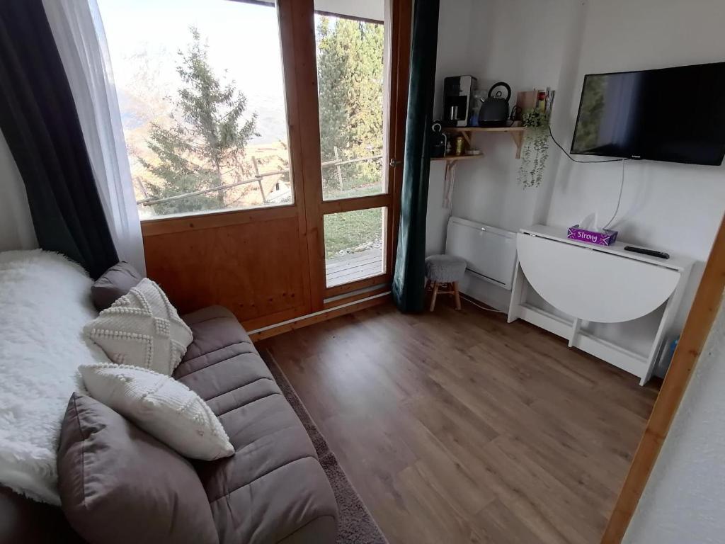 un salon avec un canapé et une grande fenêtre dans l'établissement Charmant studio ski aux pieds avec terrasse et parking - FR-1-181-2847, à Aime La Plagne