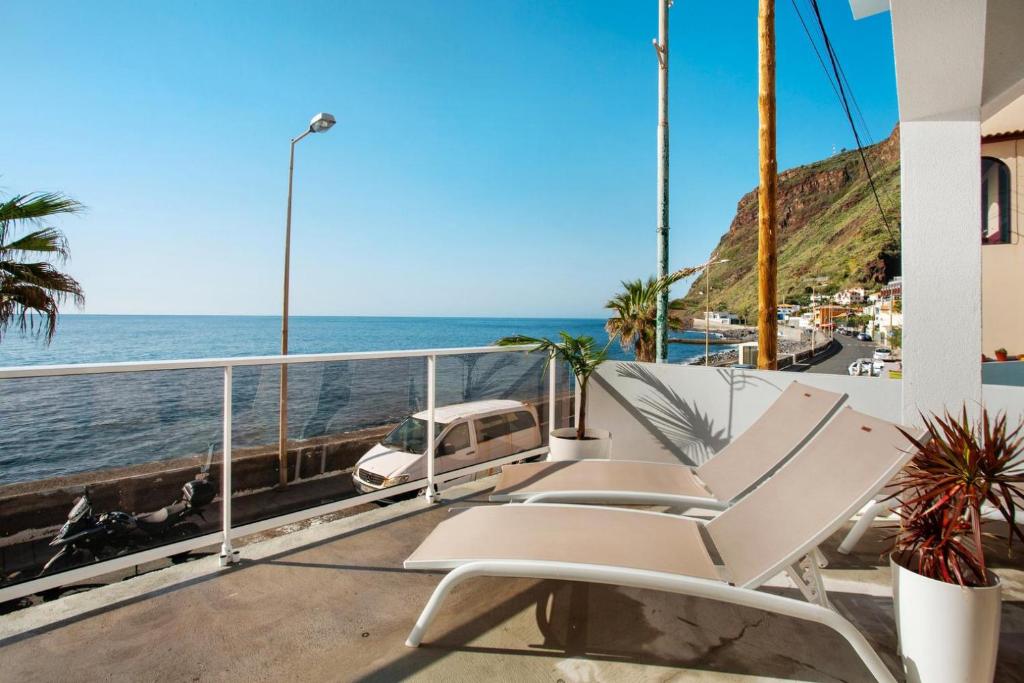 a pair of chairs on a balcony overlooking the ocean at Sunset house in Paul do Mar