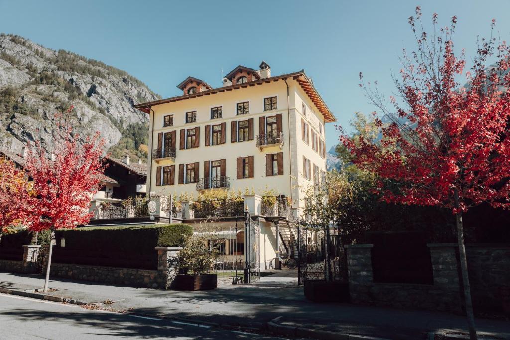 a large white building with red trees in front of it at Villa Novecento Romantic Hotel - Estella Hotel Collection & Experience in Courmayeur