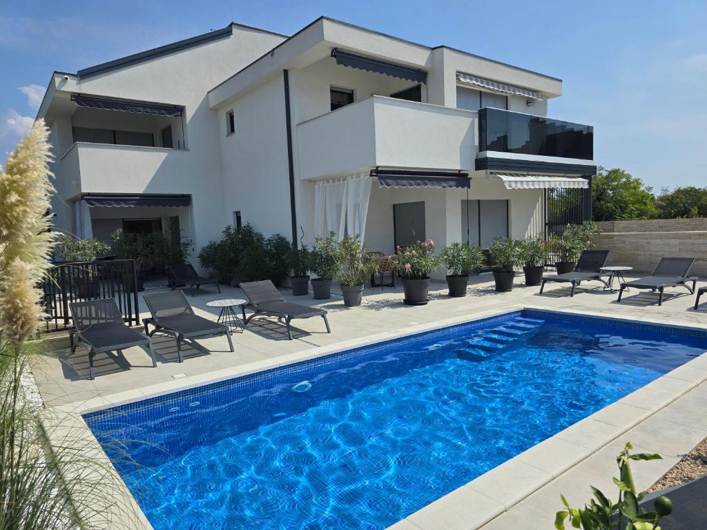 a villa with a swimming pool in front of a house at Rimac Apartments in Novalja