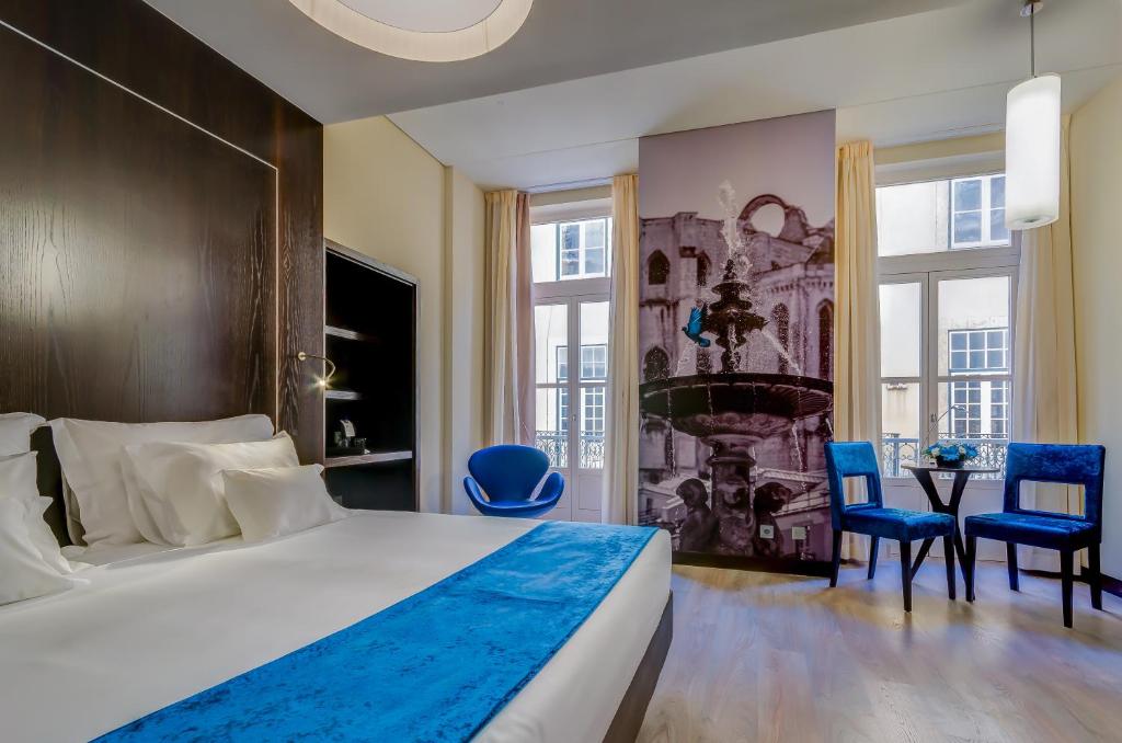 sypialnia z dużym łóżkiem i niebieskimi krzesłami w obiekcie behotelisboa w Lizbonie