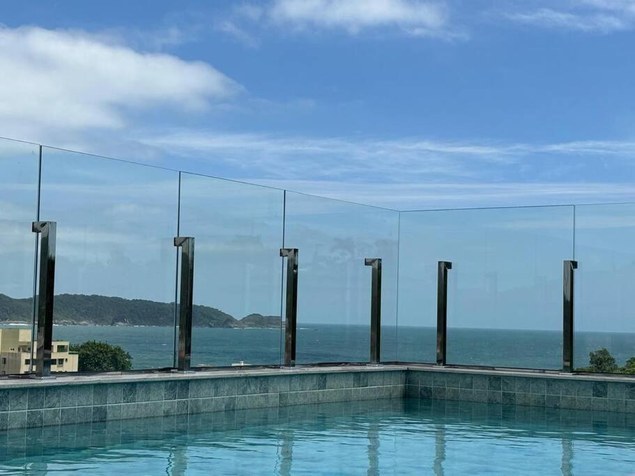 a swimming pool with a view of the ocean at Apto com piscina aquecida perto do mar in Bombinhas