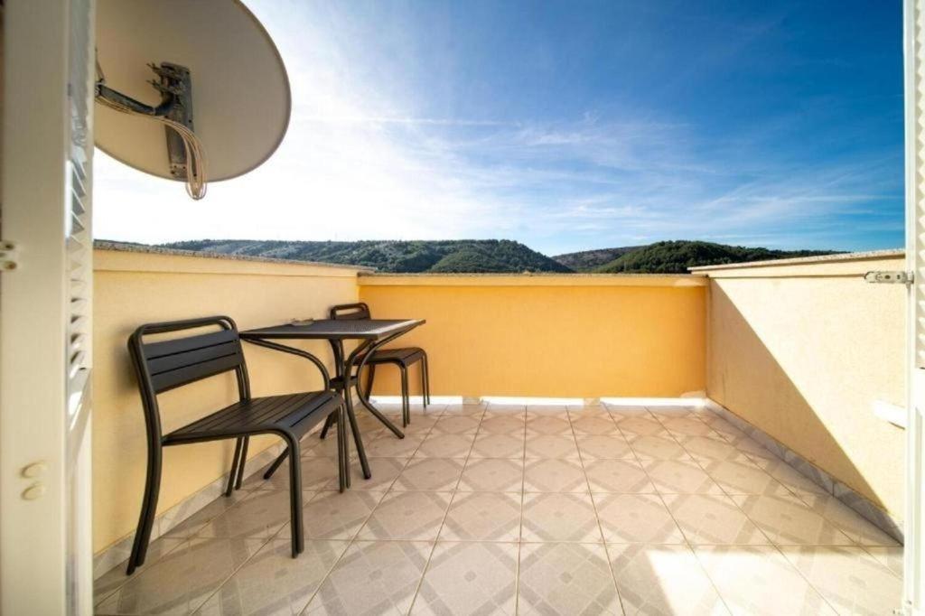 a balcony with a table and chairs and a view of mountains at Apartments BePa in Lopar