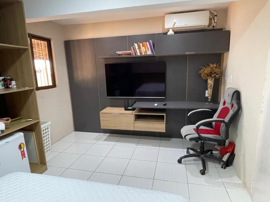 Habitación con TV, silla y escritorio. en Casa De Temporada Mandacaru, en Piranhas