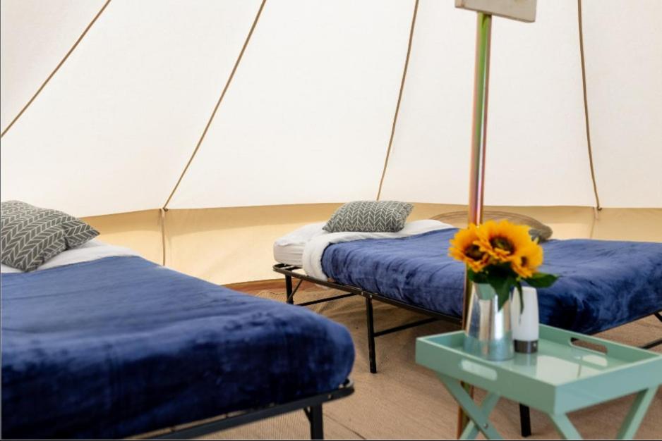 a room with two beds and a table with a vase with a flower at Duke Travel Official TT Glamping - Douglas in Kirk Braddon