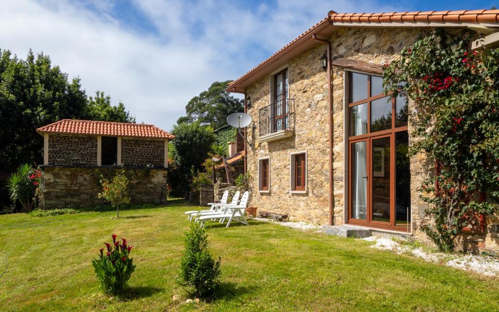 a stone cottage with a bench in the yard at Casa Balteira da Terra, Cedeira in Cedeira