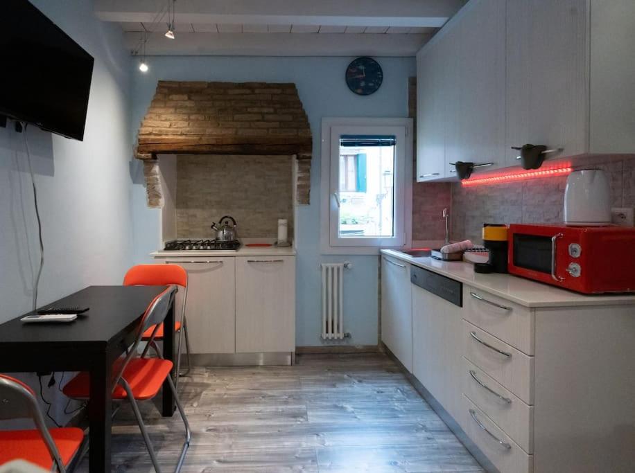 a kitchen with white cabinets and a table with a red microwave at La Casa Gialla in Chioggia