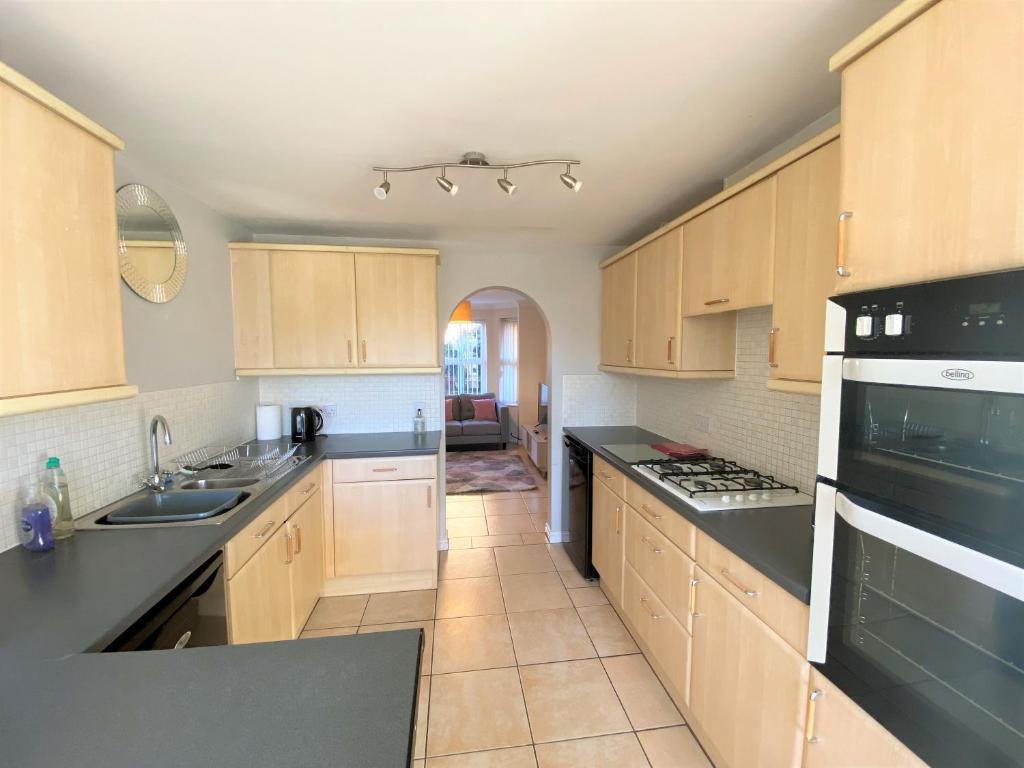 a kitchen with wooden cabinets and black counter tops at Johnson Townhouse in Wellingborough