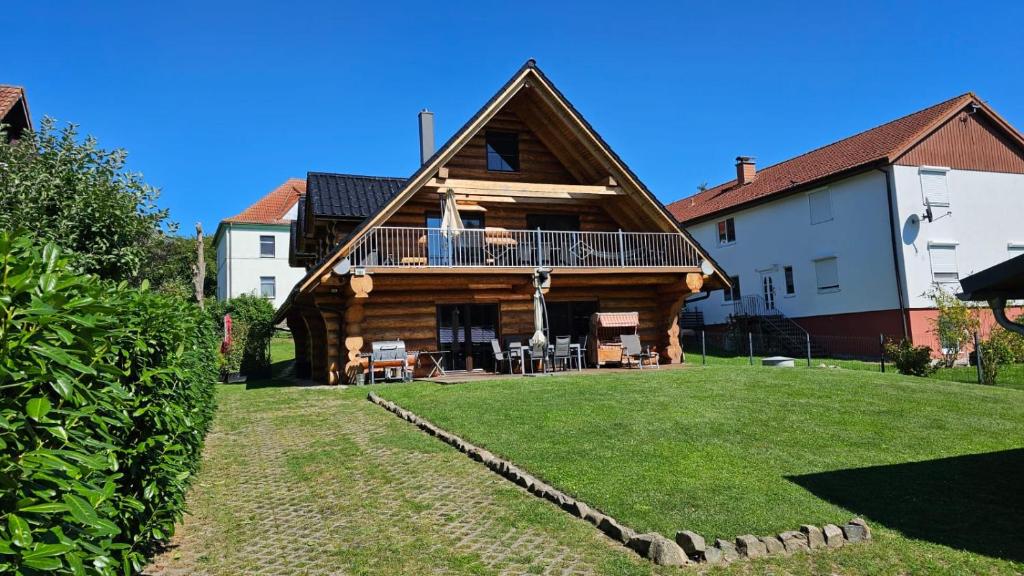 a log house with a balcony and a yard at Holzhaus Usedom mit moderner Ausstattung SAUNA und Kamin in Karnin (Usedom)